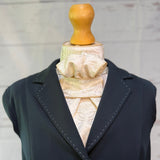 a blue jacket with an champagne equestrian stock tie underneath