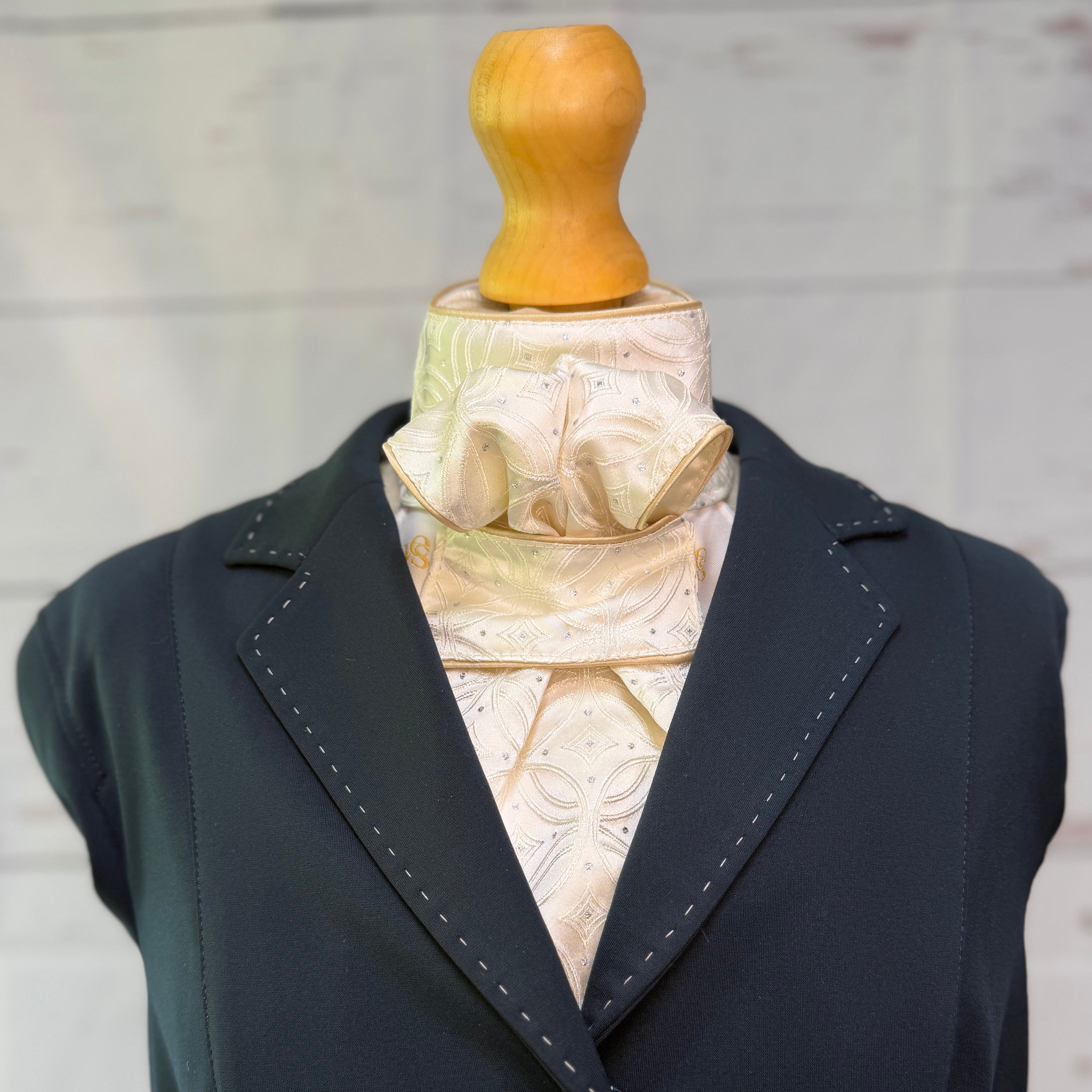 a blue jacket with an champagne equestrian stock tie underneath