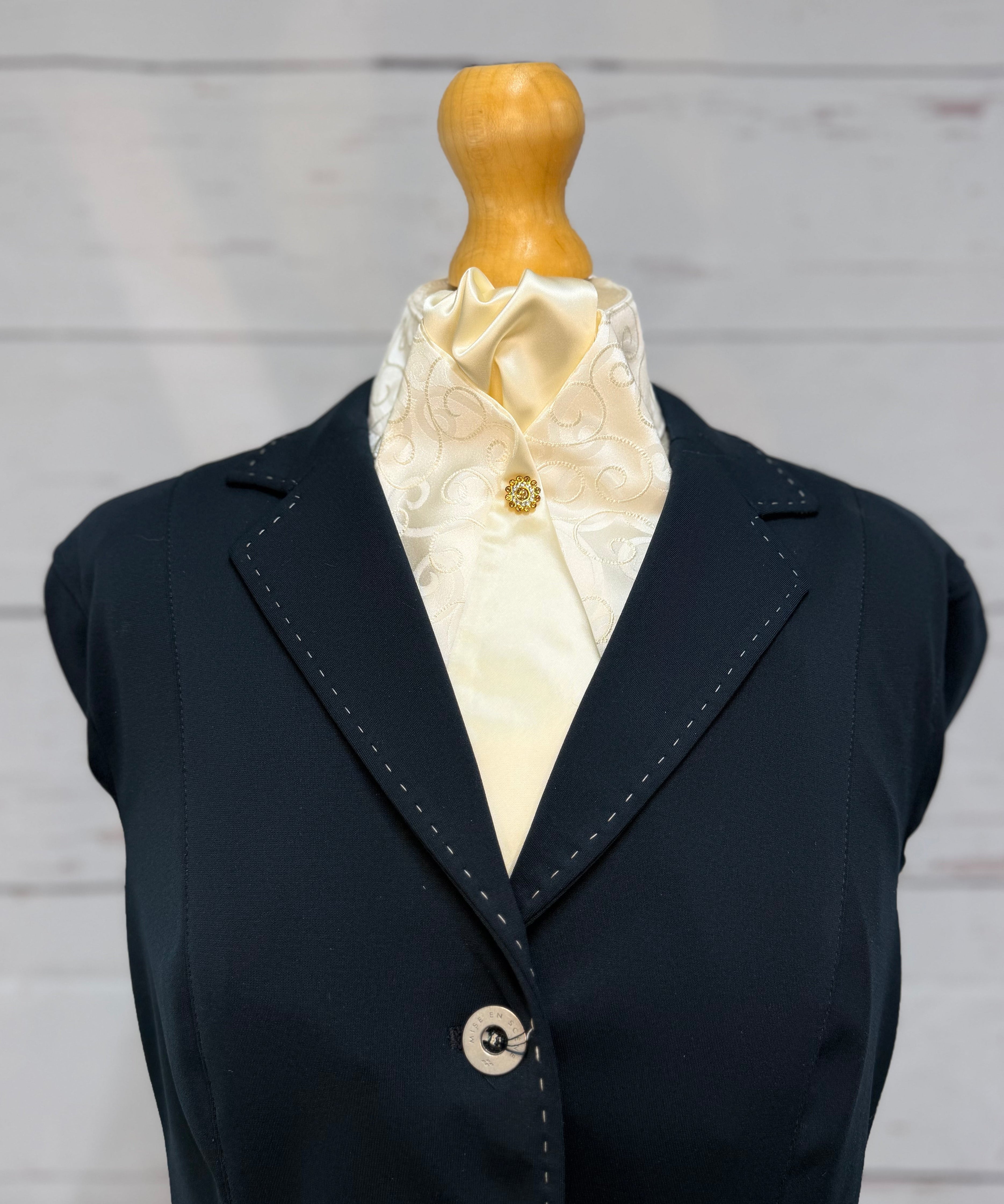 a blue jacket with a cream stock tie on a mannequin