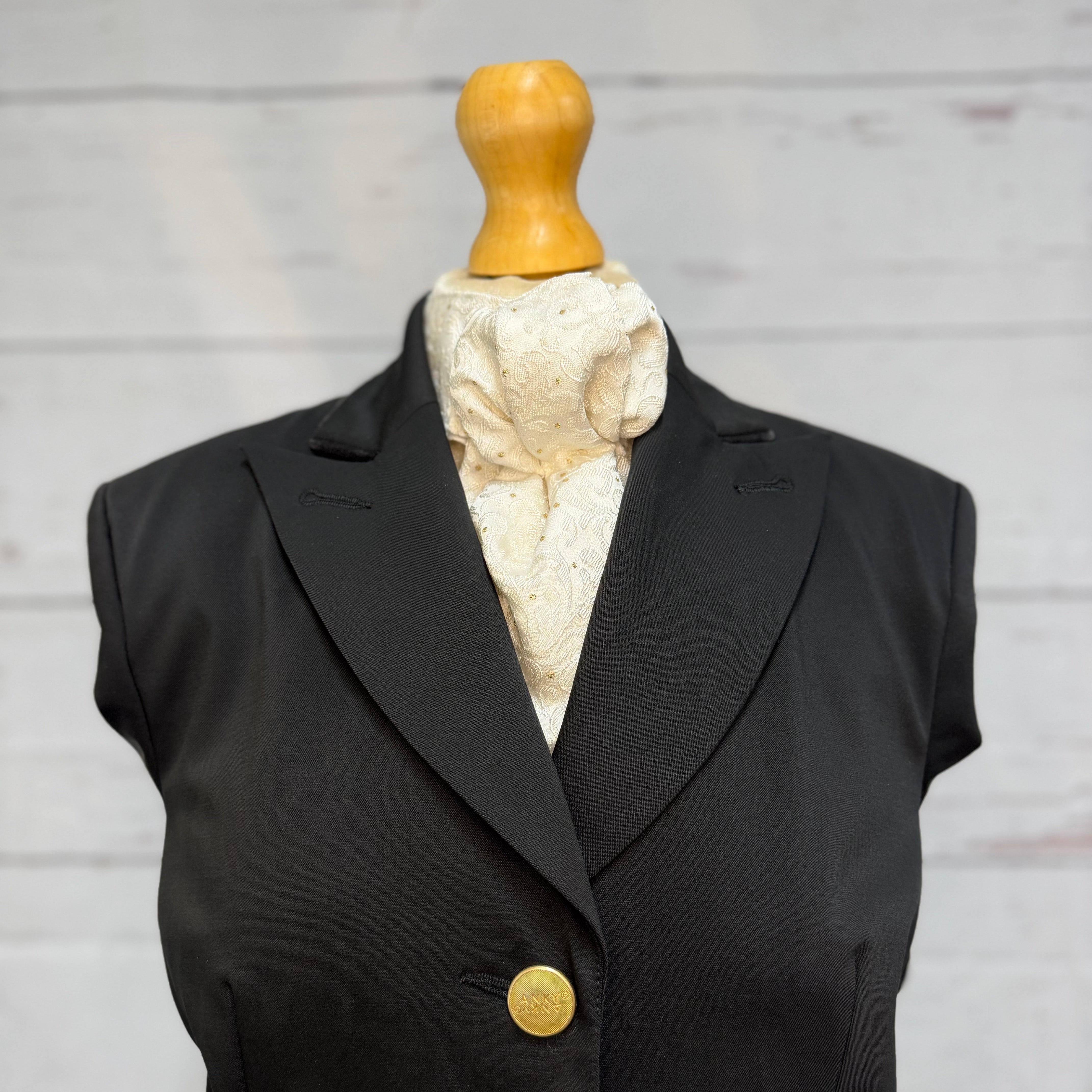 black jacket with gold and white stock tie, on a mannequin, soft background
