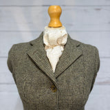 tweed jacket on a mannequin with a white and gold stock tie, soft neutral background