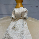 a close up of a white and gold stock tie with a neutral background