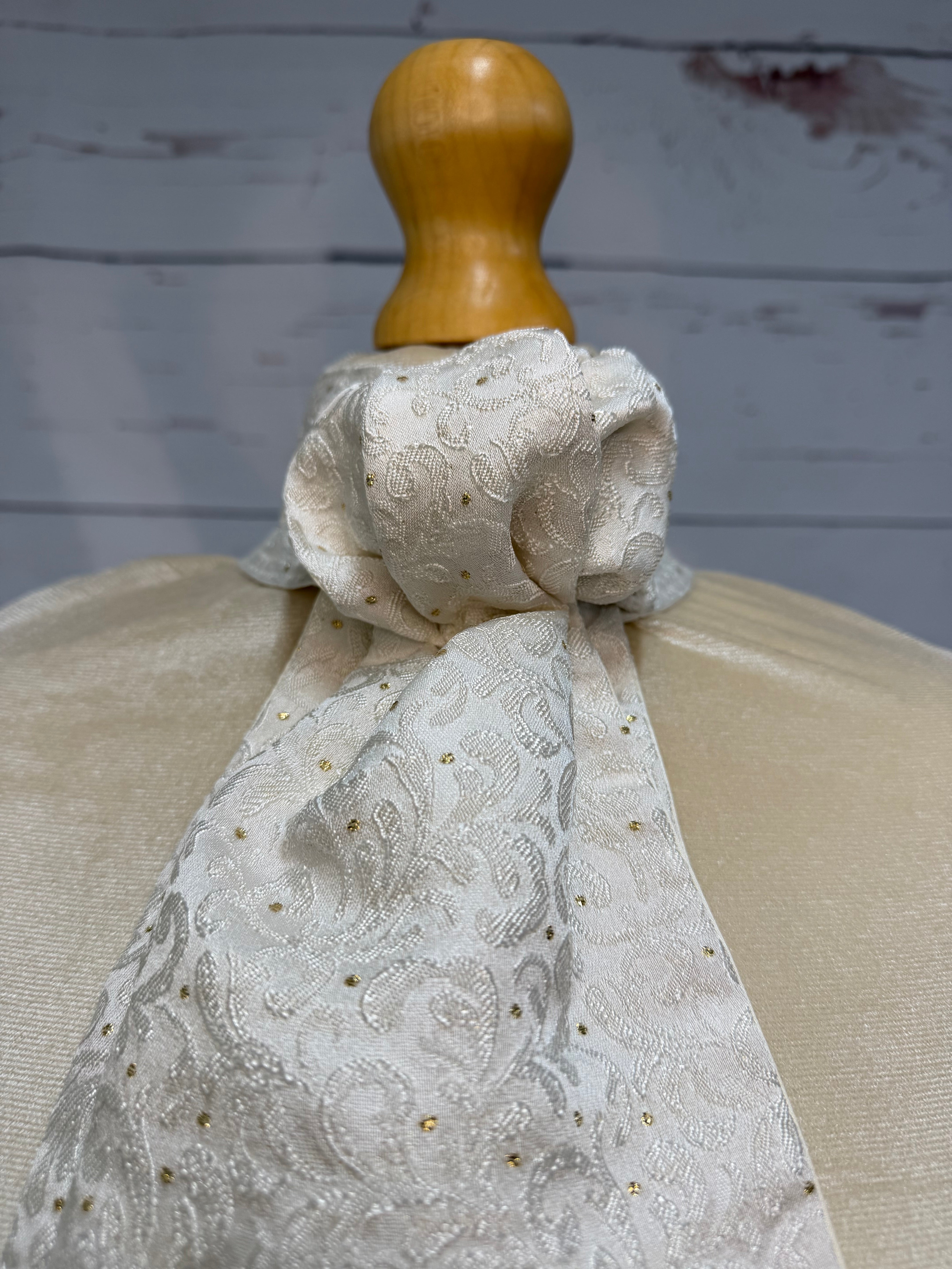 a close up of a white and gold stock tie with a neutral background