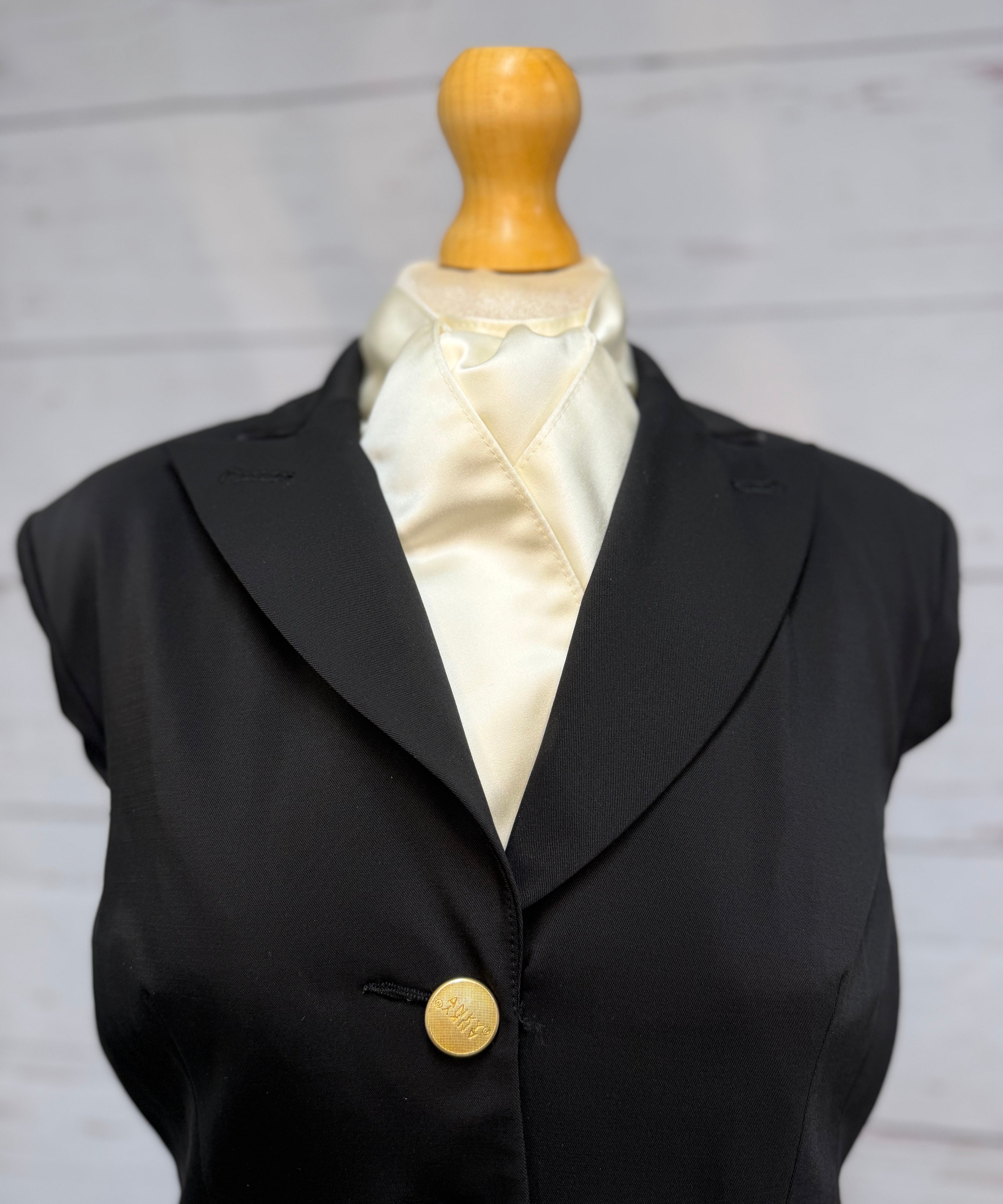 black jacket on a mannequin with a cream satin stock tie