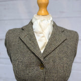 a tweed jacket on a mannequin with a cream satin stock tie 