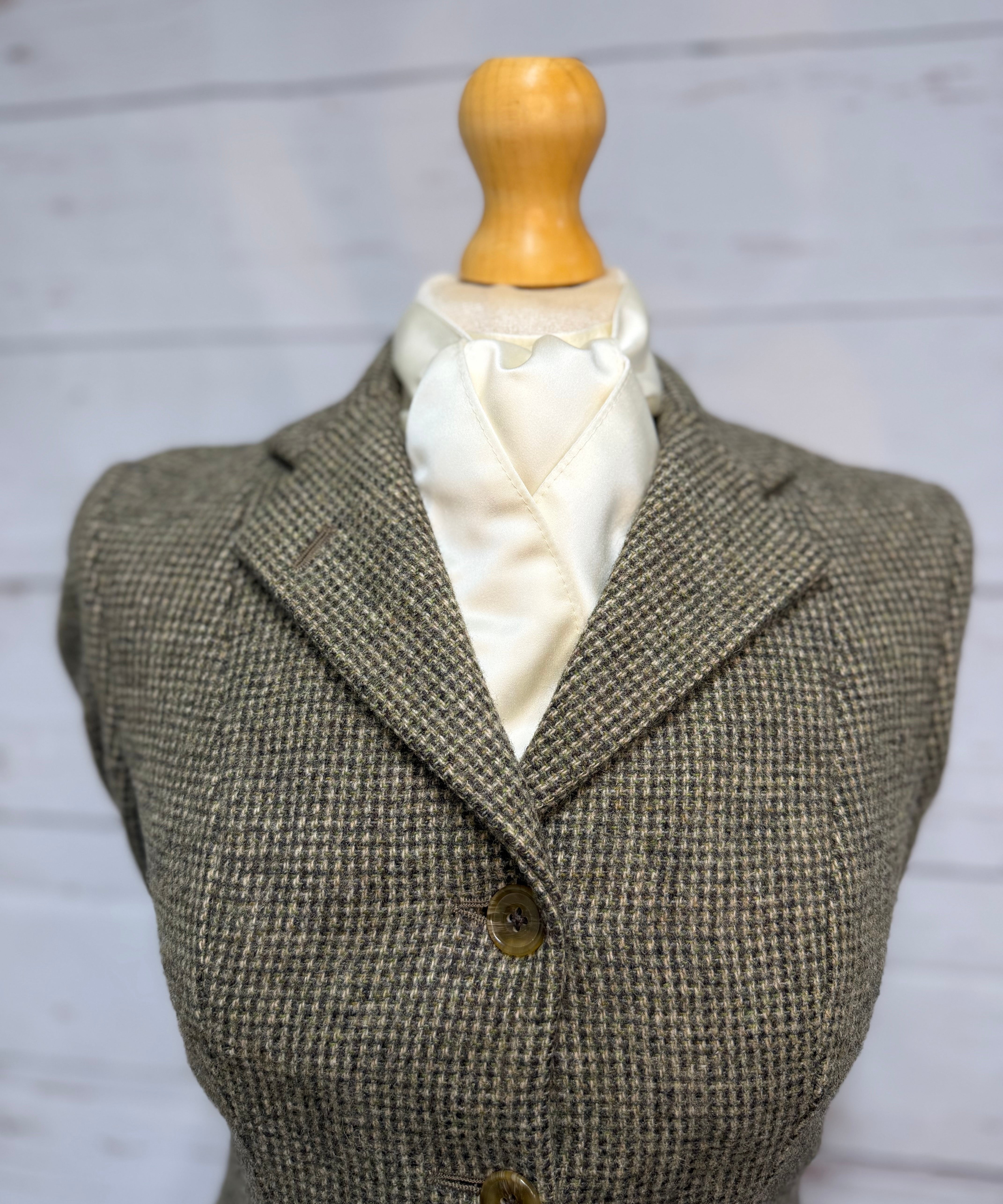a tweed jacket on a mannequin with a cream satin stock tie 