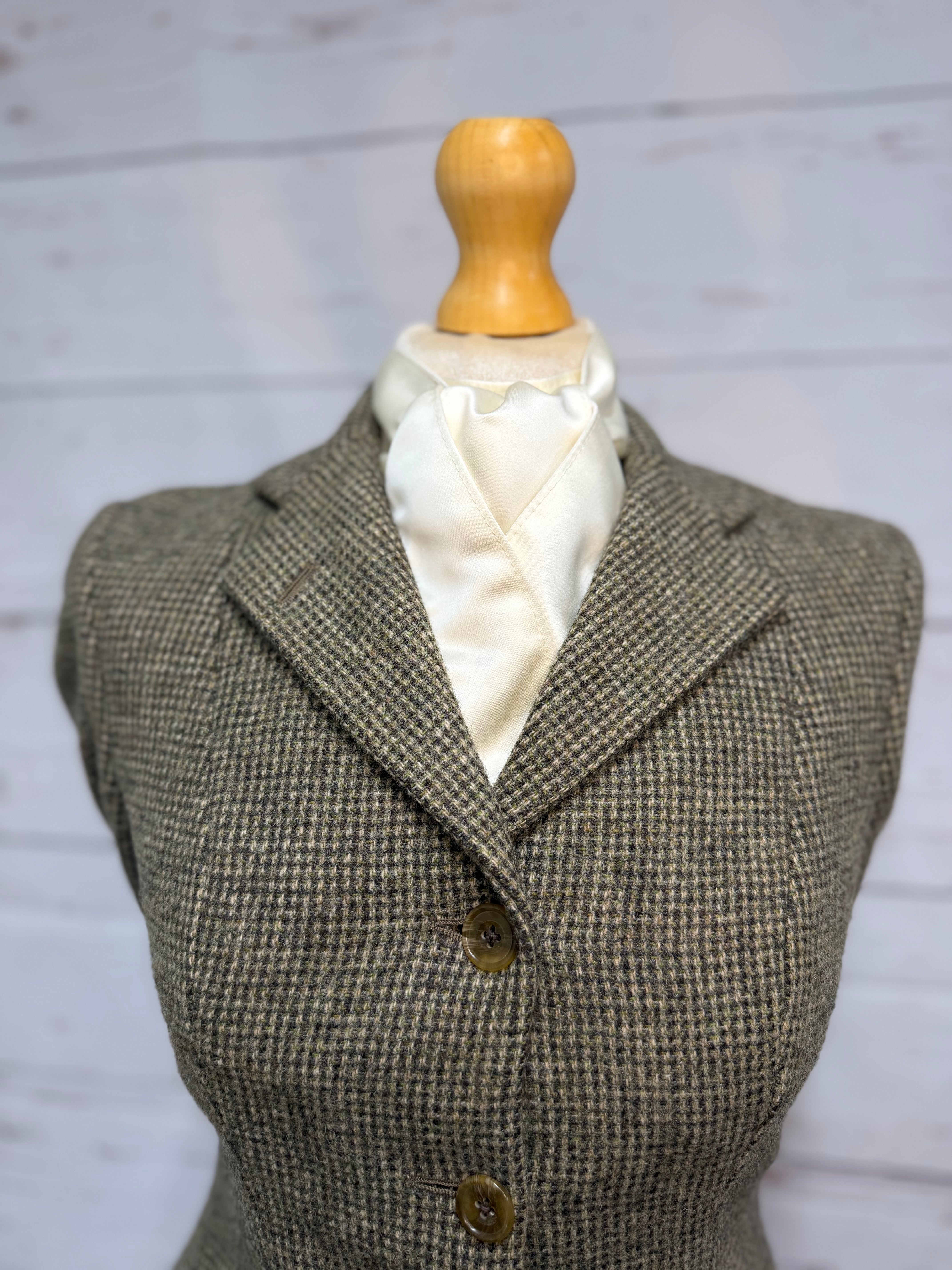 a tweed jacket on a mannequin with a cream satin stock tie 