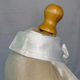 Mannequin wearing a light-colored stock tie with a wooden head on a plain background